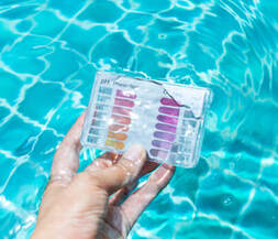 Picture of a person holding test strips to test pool chemical balance.