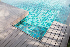 Picture of pool with blue tile and wood deck.  Wood is light in color.
