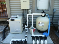Picture of a pool equipment pad that includes a sand filter, heater, pool pump, and valve assembly.
